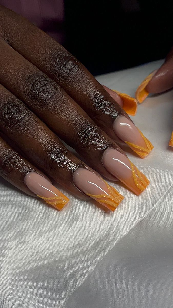 Chic Nude and Vibrant Orange Nail Design with Intricate Detailing and Sharp Square Tips