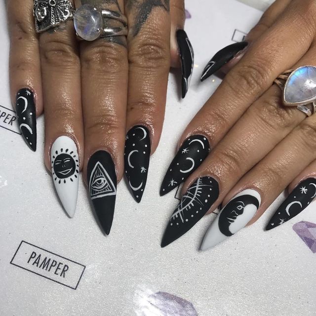 Bold Black and White Celestial Nail Design with Intricate Motifs and Edgy Stiletto Shape.