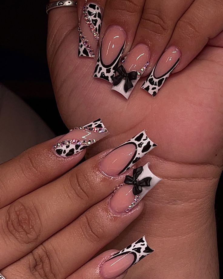 Playful Chic: Elegant Nail Design Blending Nude and Bold Black-and-White Patterns with Cow Print, Bows, and Sparkling Rhinestones