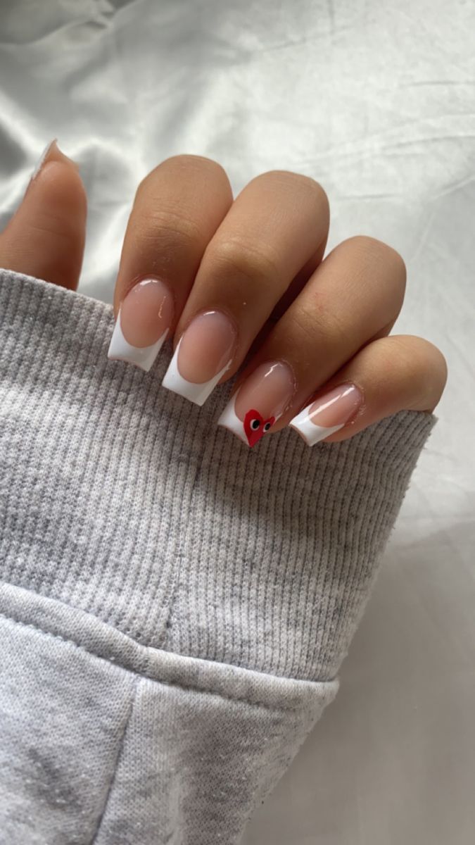 Chic French Tip Manicure with Whimsical Heart Accent.