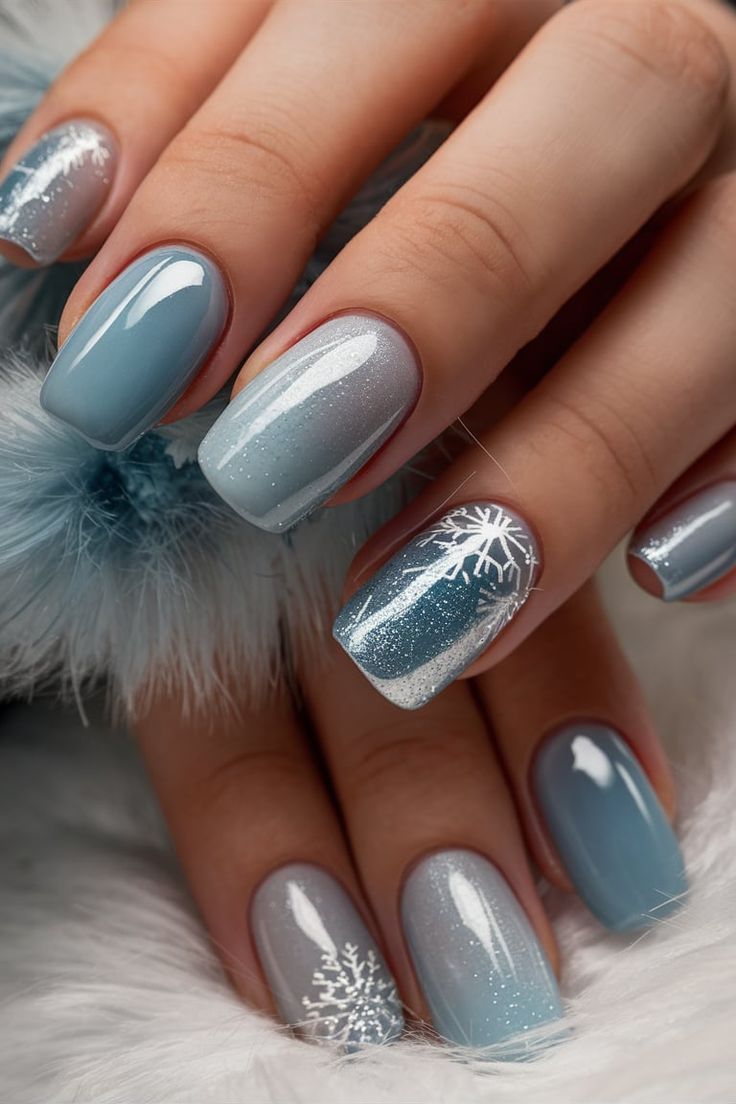 Chic Winter Nail Design with Soft Blue, Silver, and Frosty Snowflake Patterns.