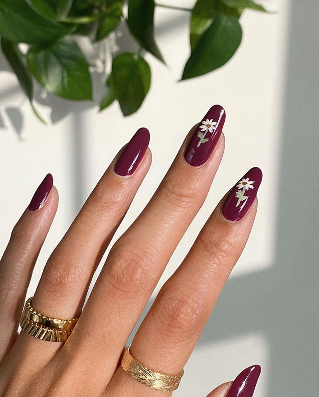 Sophisticated Almond-Shaped Nails: Rich Burgundy Polish with Elegant Floral Designs and Chic Gold Rings.