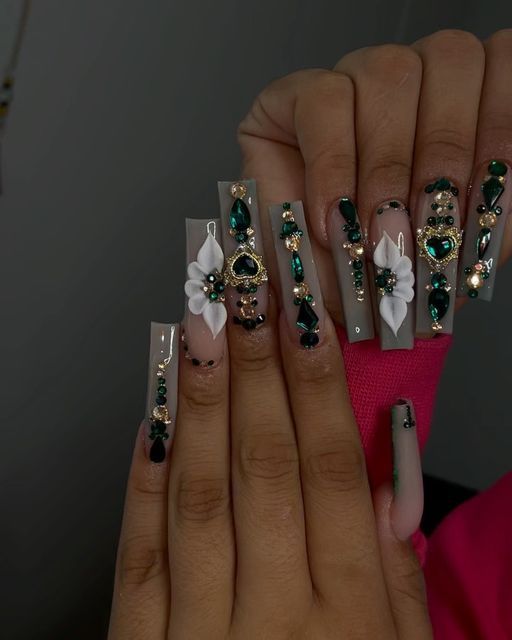 Luxurious Nail Design: Long Transparent Acrylics with Gemstones, Gold Accents, and Floral Embellishments.