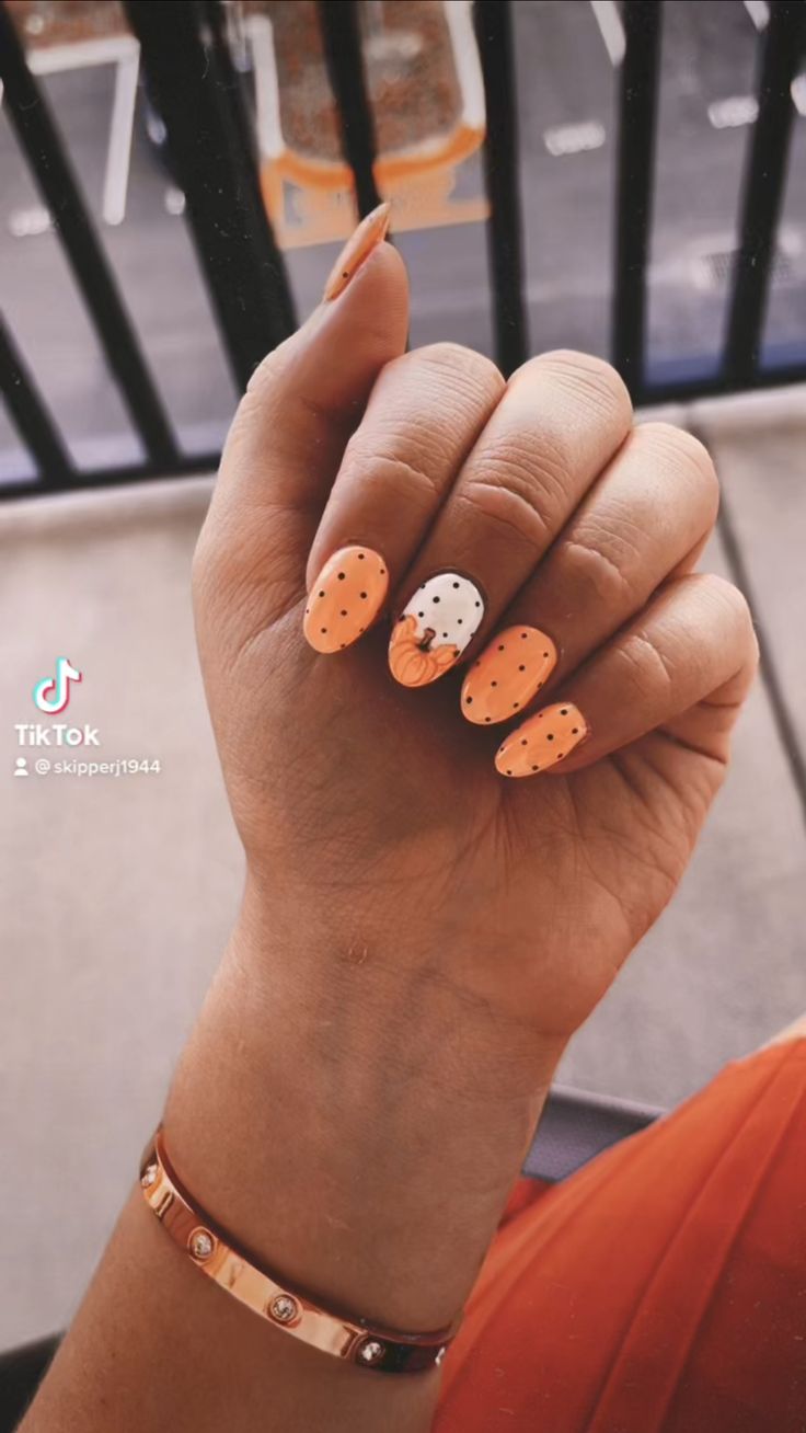 Autumn-Inspired Festive Nail Design with Vibrant Orange, Playful Polka Dots, and Pumpkin Accent.