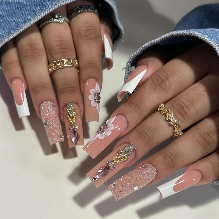 Elegant Nude and Glitter Nail Design with Floral Accents and Jewels.