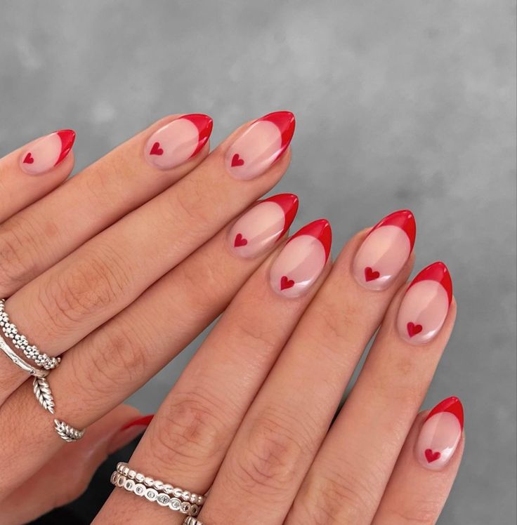 Chic Heart-Embellished Nail Design with Striking Red French Tips for a Flirty Look.