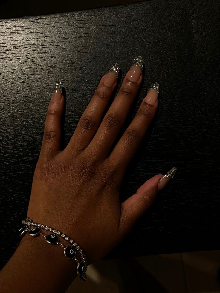 Sophisticated Almond-Shaped Nude Nails with Sparkling Silver Accents and Coordinating Bracelet.