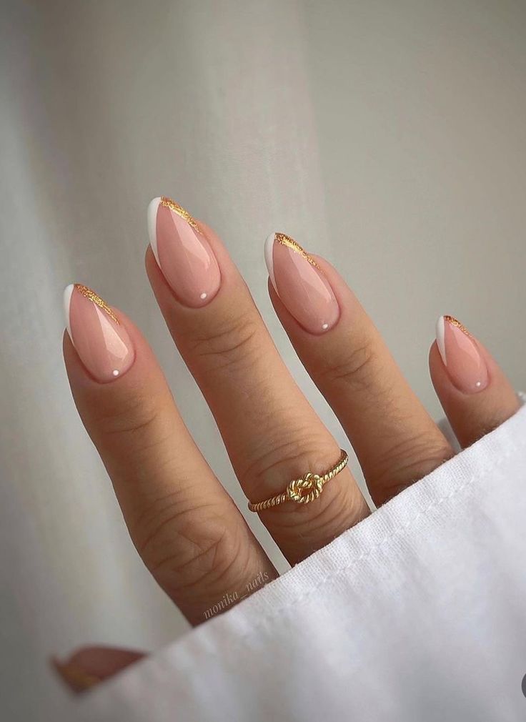 Sophisticated Nude Nail Design with White Tips and Gold Accents on Almond Shape.