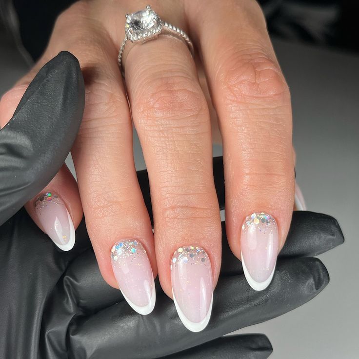 Chic Soft Pink Ombre Nail Design with Delicate White Tips and Holographic Glitter Accents.