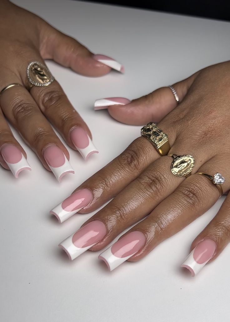 Chic Nail Design: Soft Pink Base with Bold White Tips and Glamorous Rings.