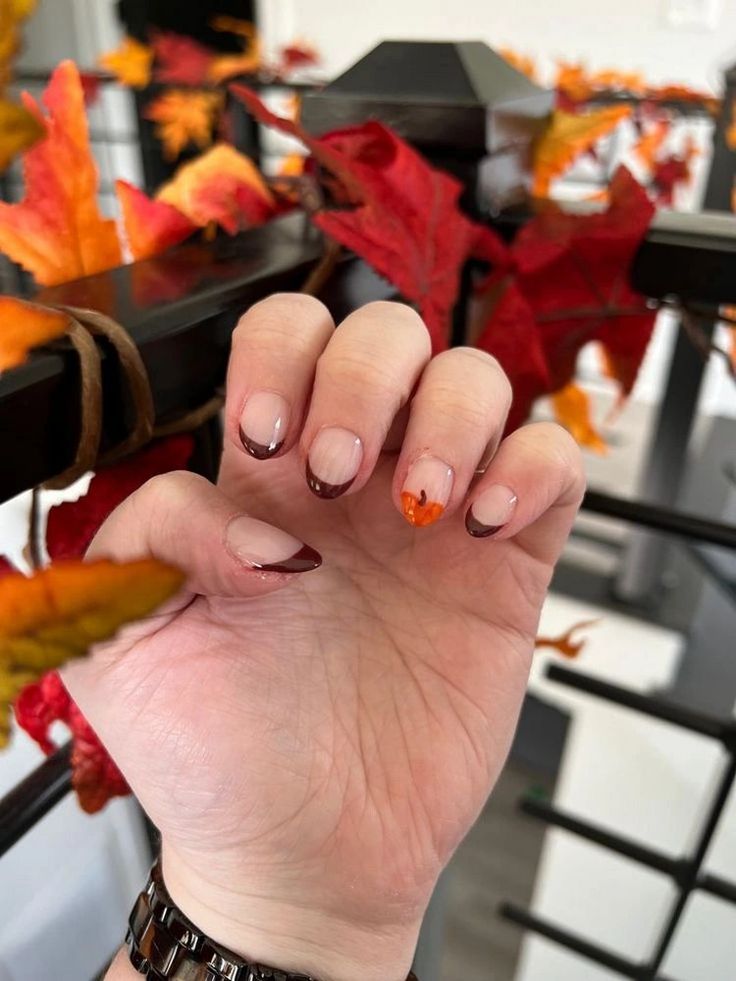 Chic Autumn French Manicure: Nude and Burgundy with Orange Leaf Detail.