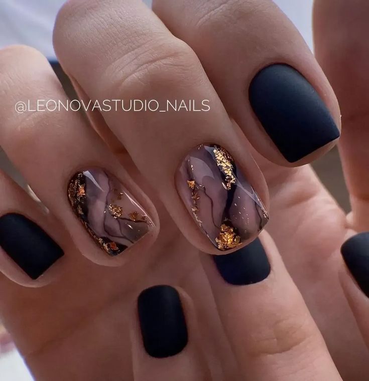 Chic Matte Black and Marbled Nail Design with Elegant Gold Accents.