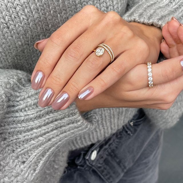 Chic Almond-Shaped Nails with Glossy Nude-Pink Finish Paired with Elegant Rings and Cozy Knit Sweater.