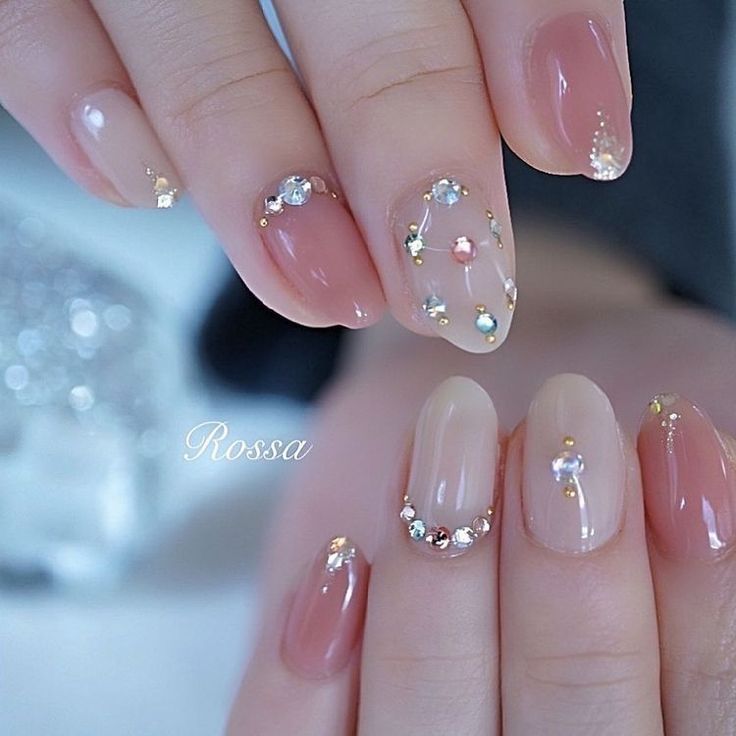 Sophisticated Nude and Pale Pink Nail Design with Glamorous Embellishments.