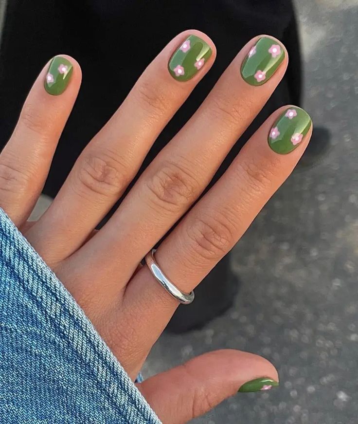 Chic Deep Green Nail Design with Delicate Pink Floral Accents for a Modern Aesthetic.