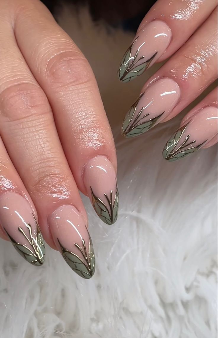 Chic Almond-Shaped Nail Design: Nude Base with Intricate Green Leaf Patterns and Glossy Finish.