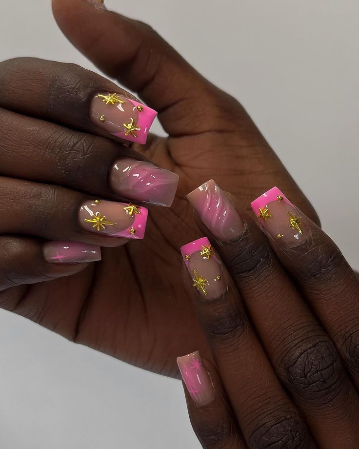 Chic Pink-Tipped Nail Design with Gold Star Accents and Artistic Swirls