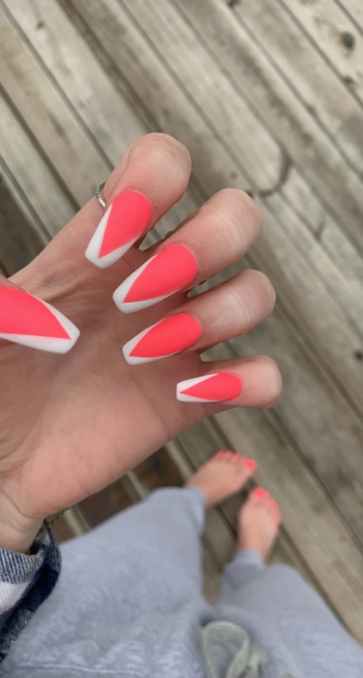 Vibrant Coral Stiletto Nails with Sleek White Chevron Accents for a Bold Statement.