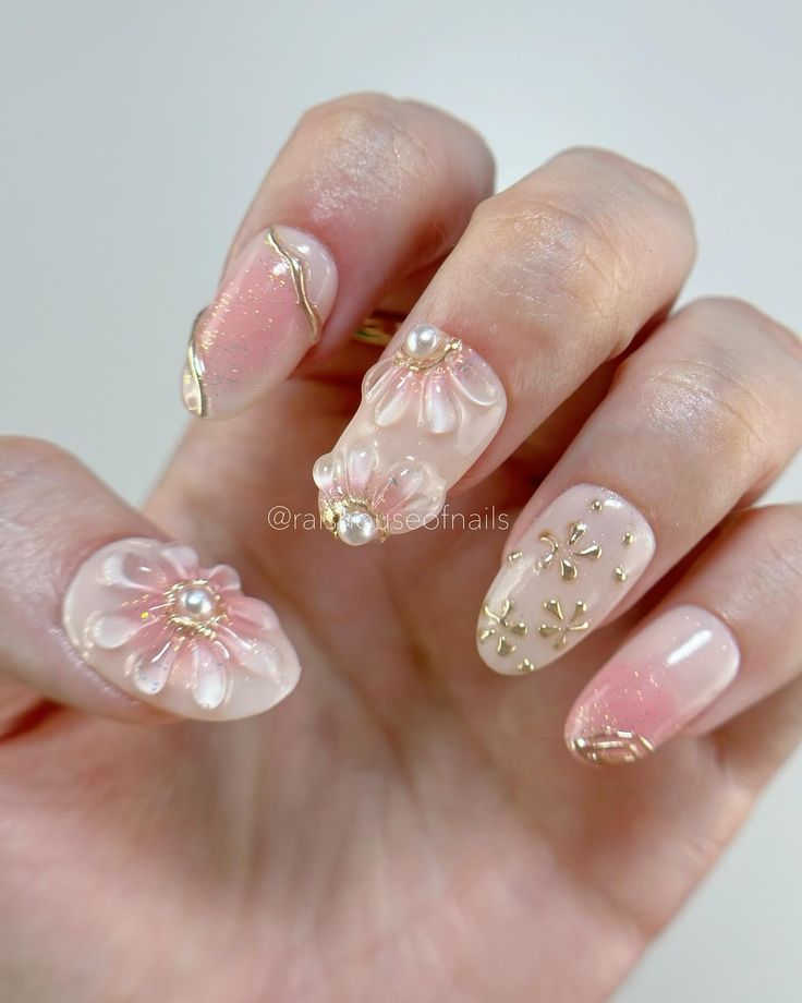 Chic Floral Nail Design with Pink Hues and Elegant Gold Accents