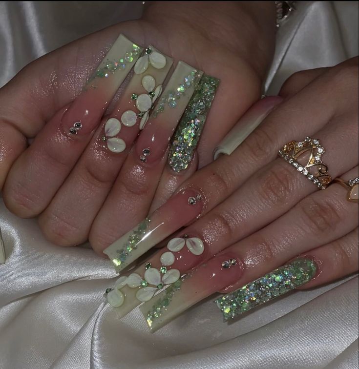 Elegant Iridescent Green Nail Art with Floral Accents and Rhinestones.