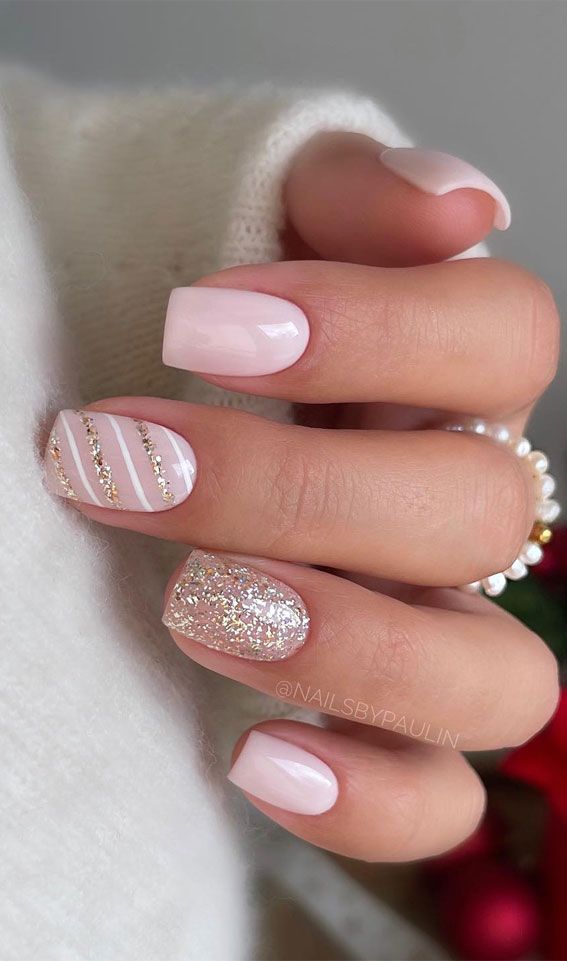 Chic Festive Nail Design: Soft Pink Base with White Stripes and Glitter Accents.