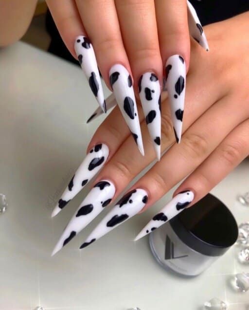 Bold and Whimsical Cow Print Stiletto Nails: A Unique Statement Design.