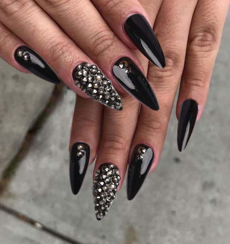 Glamorous Black Stiletto Nails with Glossy Finish and Sparkling Embellishments for a Bold Fashion Statement.