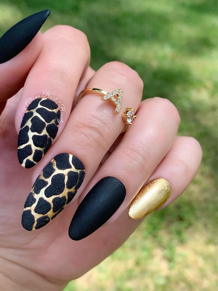 Chic Nail Design with Matte Black, Gold Accents, and Playful Giraffe Print.