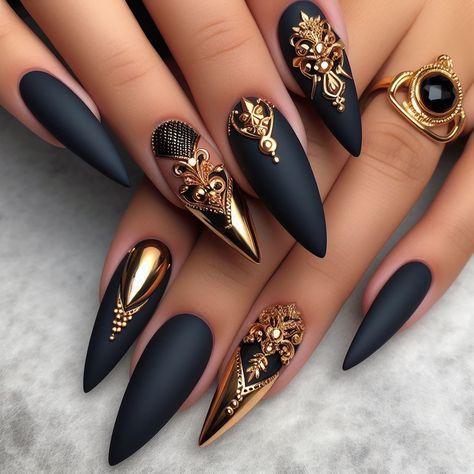 Dramatic Matte Black Stiletto Nails with Intricate Gold and Gemstone Embellishments for a Bold Statement.