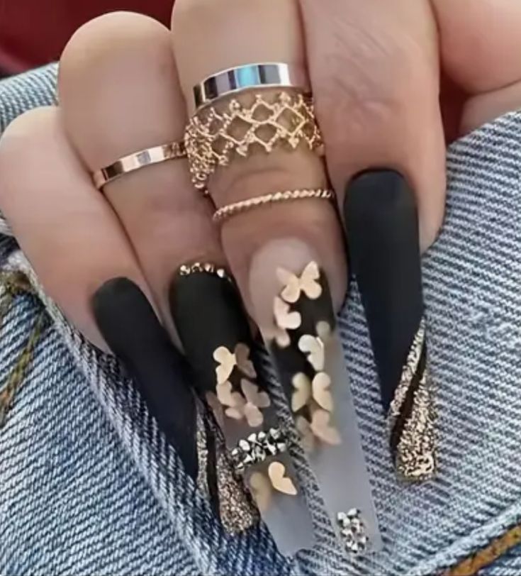 Chic Matte Black and Glossy Clear Nail Design with Gold Accents and Butterfly Embellishments.