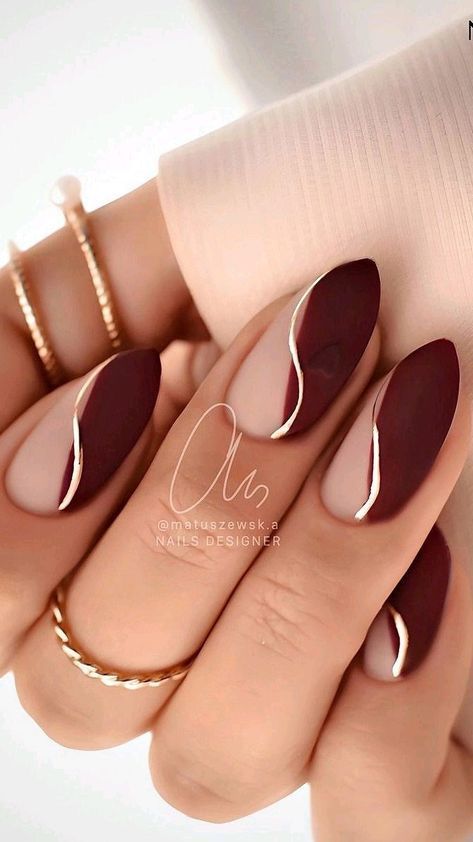 Sophisticated Nail Design: Deep Burgundy and Nude with Wavy Gold Accent.