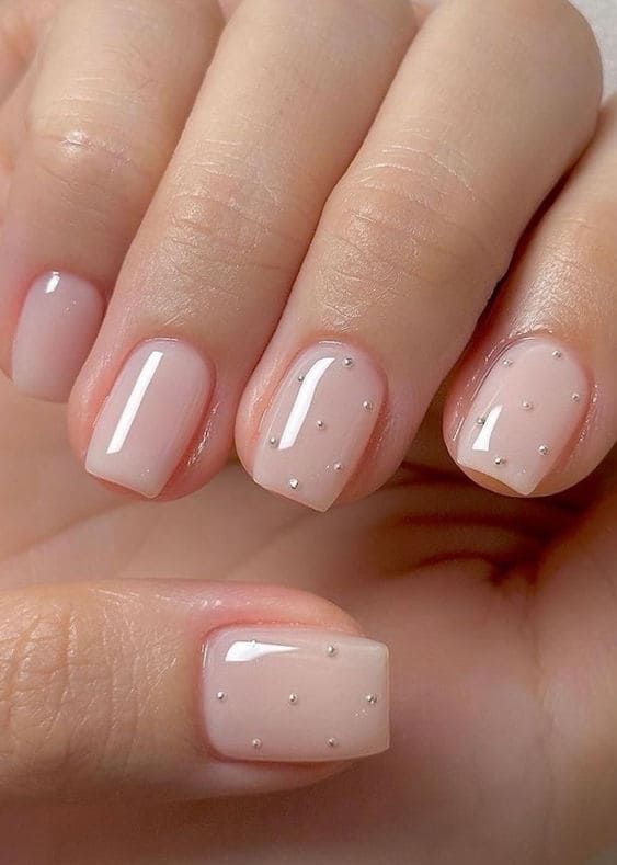 Chic Elegant Nude Nail Design with Glossy Finish and Subtle 3D Embellishments.