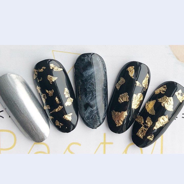 Luxurious Nail Design with Matte Black, Gold Leaf Accents, and Marbled Effect