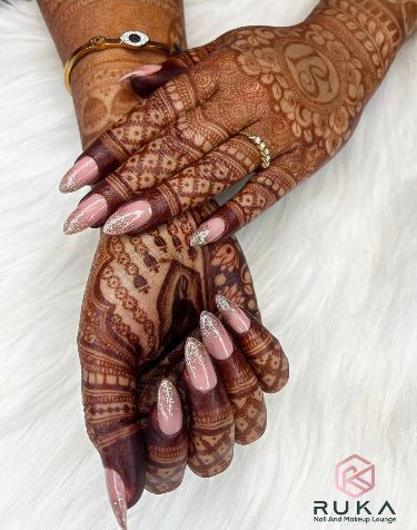 Sophisticated Nude and Glitter Nail Design with Intricate Henna Patterns for Elegant Occasions.