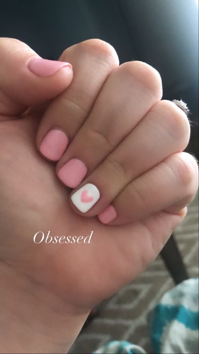 Charming Soft Pink Nail Design with Heart Accents for a Playful Touch.