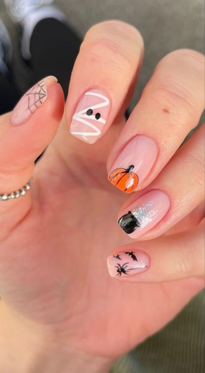 Playful Whimsical Halloween Nail Design with Mummy, Pumpkin, and Spider Motifs.