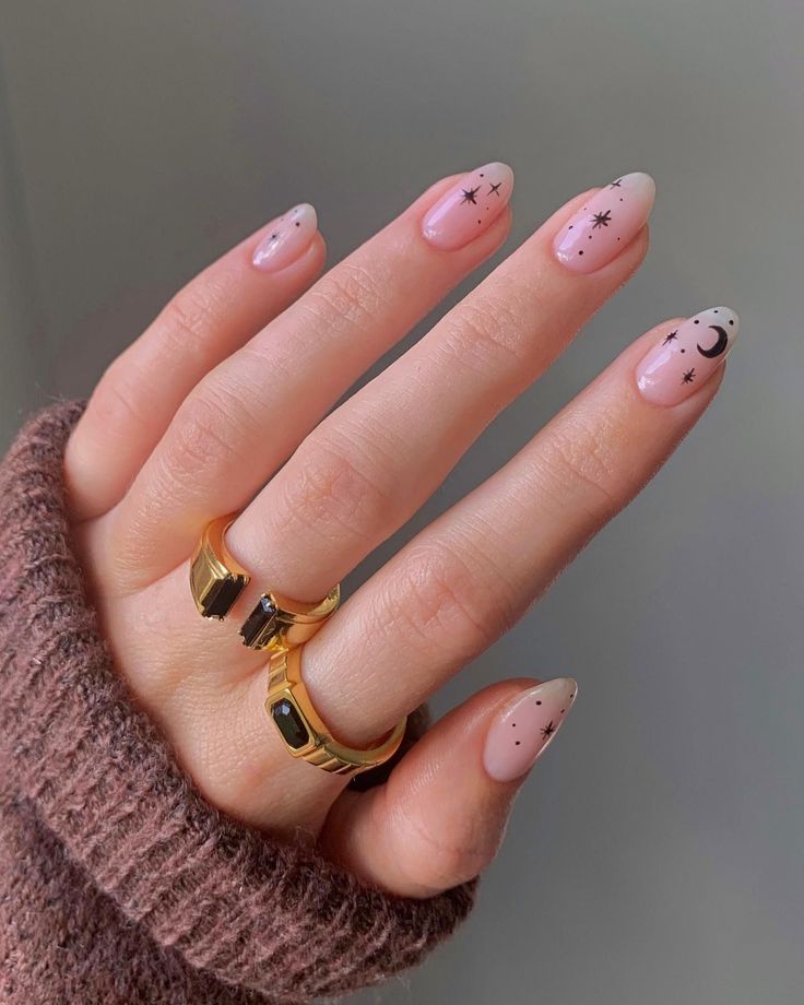 Whimsical Celestial Nail Design: Soft Nude Base with Star and Moon Accents on Almond Shaped Nails.