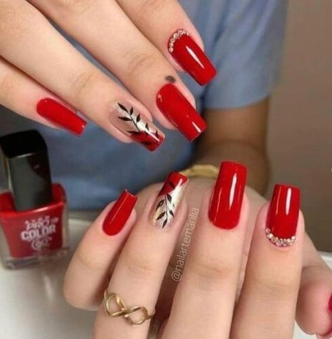 Elegant Vibrant Red Nail Design with Metallic Leaf Accents and Rhinestone Embellishments.