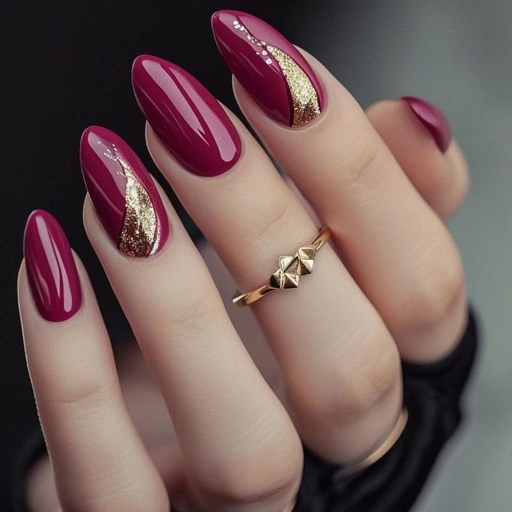 Sophisticated Almond-Shaped Nails with Burgundy Polish and Striking Gold Accents.