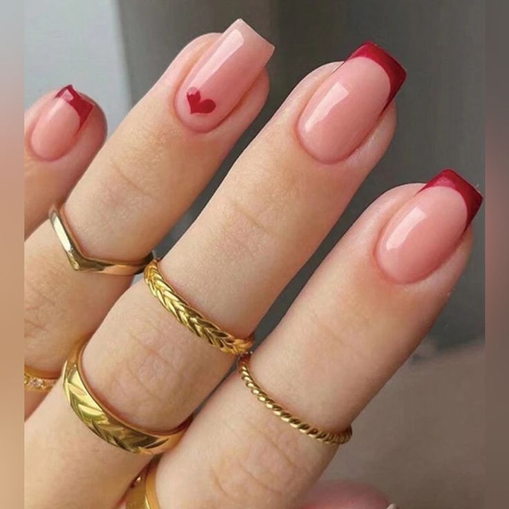 Chic Soft Pink Nails with Bold Red Tips and Heart Accent for a Romantic Touch.