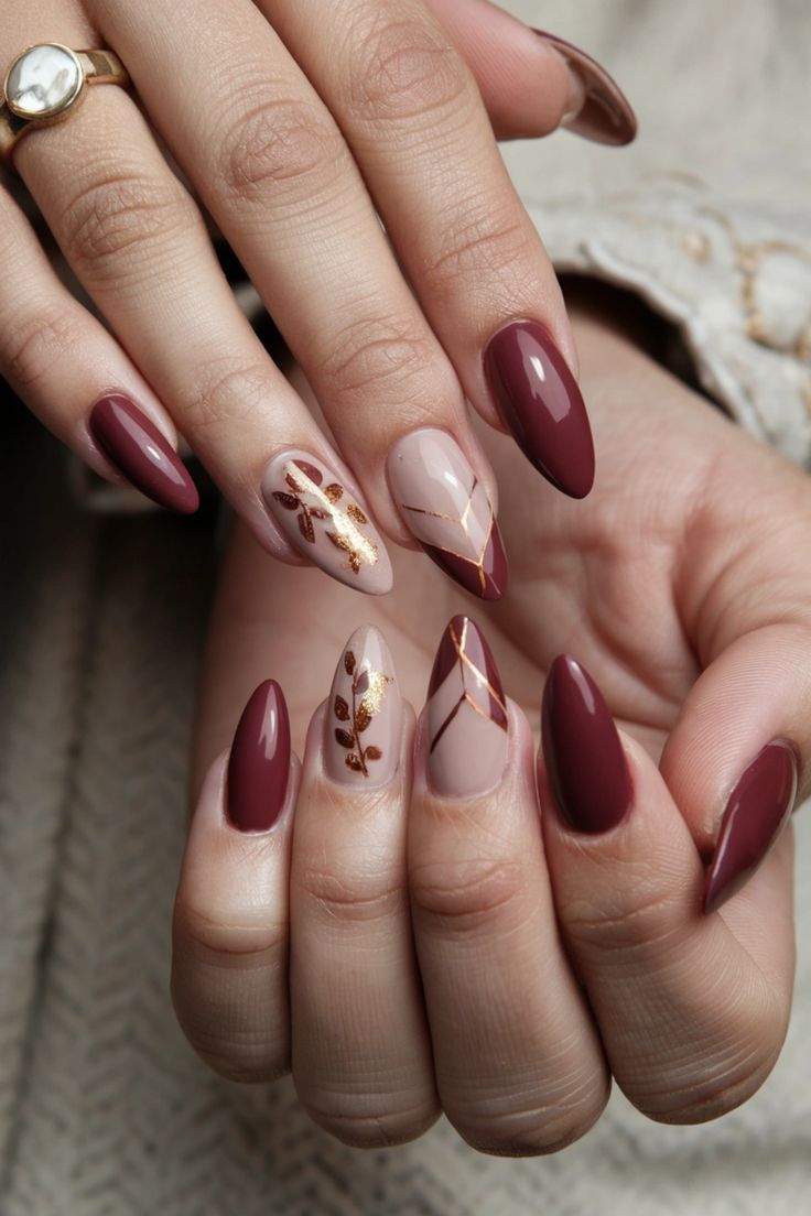 Sophisticated Almond-Shaped Nail Design in Deep Burgundy and Nude with Gold Accents.