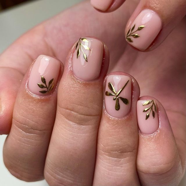 Chic Nude Nail Design with Gold Leaf and Elegant Floral Accents