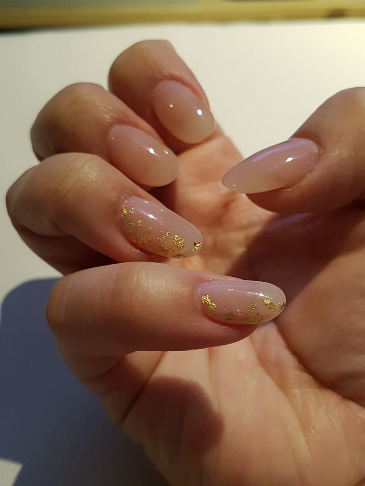 Sophisticated Nude Nail Design with Glossy Finish and Delicate Gold Glitter Accents