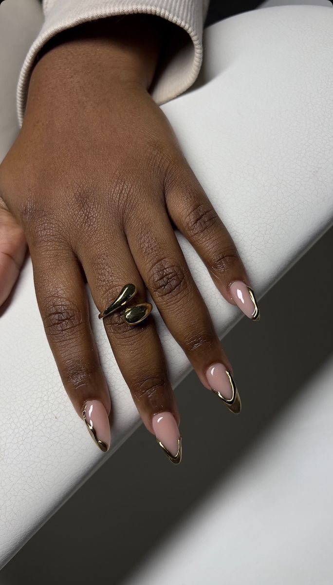 Chic Almond-Shaped Nails: Soft Nude Base with Glamorous Gold Tips.