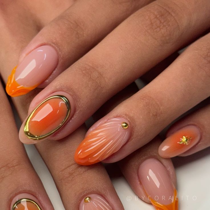 Elegant Orange and Nude Gradient Nail Design with Gold Accents and Textured Patterns.