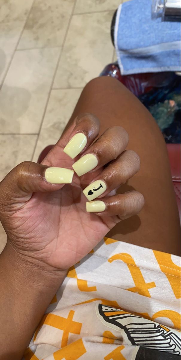 Cheerful Bright Yellow Nail Design with Whimsical Heart Accent on Square Tips.