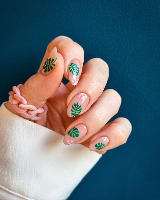 Chic Botanical Nail Design with Green Leaf Motifs and Soft Pink Swirls.