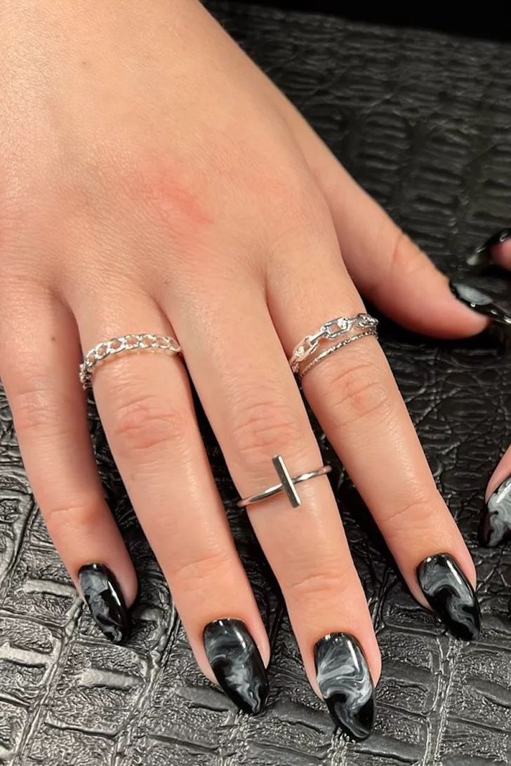 Elegant Black and White Marble Nail Design with Sharp Tips and Silver Accents