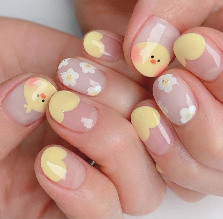 Cheerful Spring Nail Design with Soft Yellow Hearts, Chick Motifs, and Delicate White Flowers.