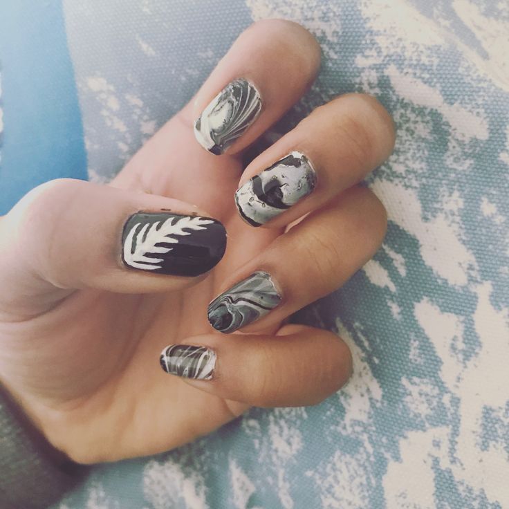 Elegant Black, White, and Grey Nail Design with Intricate Marble Patterns and Bold Leaf Motif.